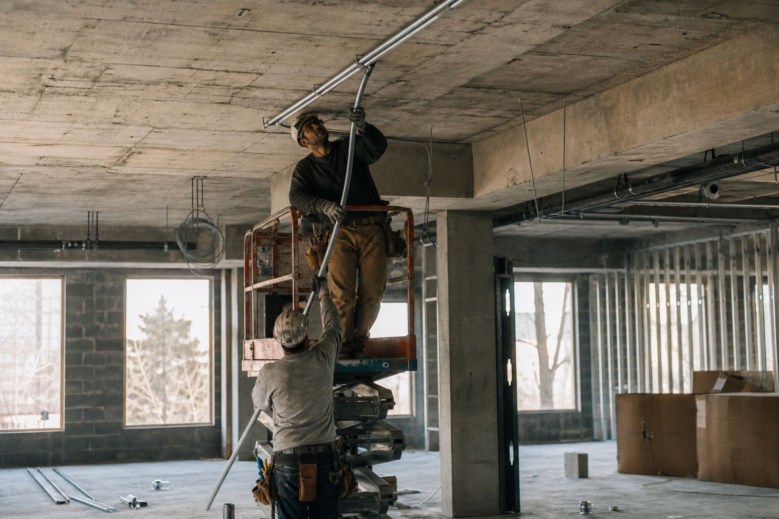Electricians pulling conduit in a commercial building under construction